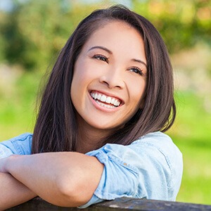 Woman's smile compared with porcelain veneer color chart during cosmetic dentistry checkup